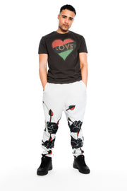 Our Model Jon Paul is wearing a black Tee shirt with our signature red black and green love heart, and white joggers with the power is love fist holding a red black and green arrows of power and love